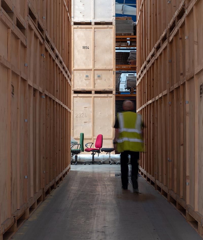 Man in high-vis jacket walking between storage containers