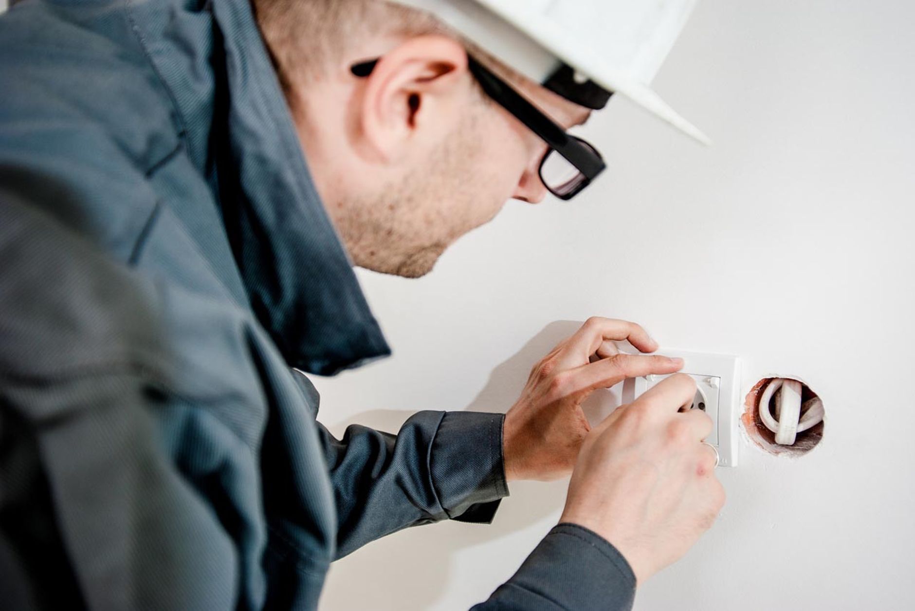 A man in a hard hat doing electrical work - sustainability