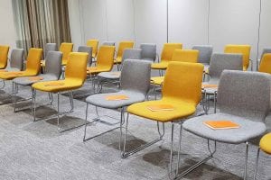 Business room with grey and orange chairs, each with an orange notepad sitting on them